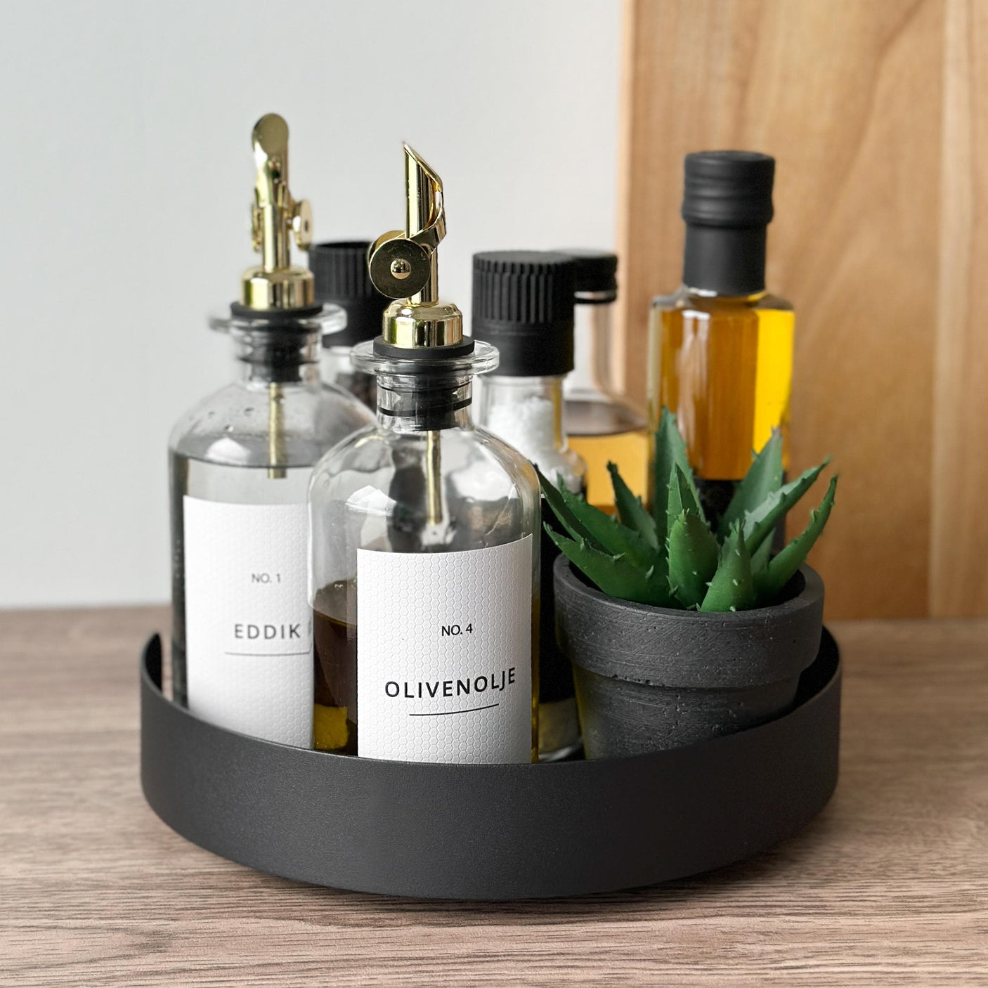 Elegant snurrebrett med flasker og dekorativ plante – kombinerer funksjon og stil, og holder kjøkkenbenken både ryddig og innbydende.