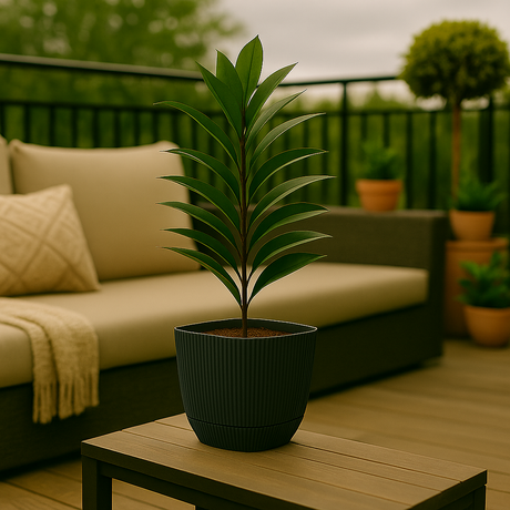 Plante i mørkegrå, rillet plastpotte plassert på bord i stilfull veranda med utemøbler og grønne omgivelser.
