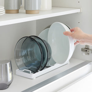 Skålstativ i hvit plast med silikonføtter, brukt til stablet kjøkkenutstyr.