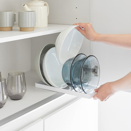 Hvit holder til skåler som gir bedre orden i skap og hyller