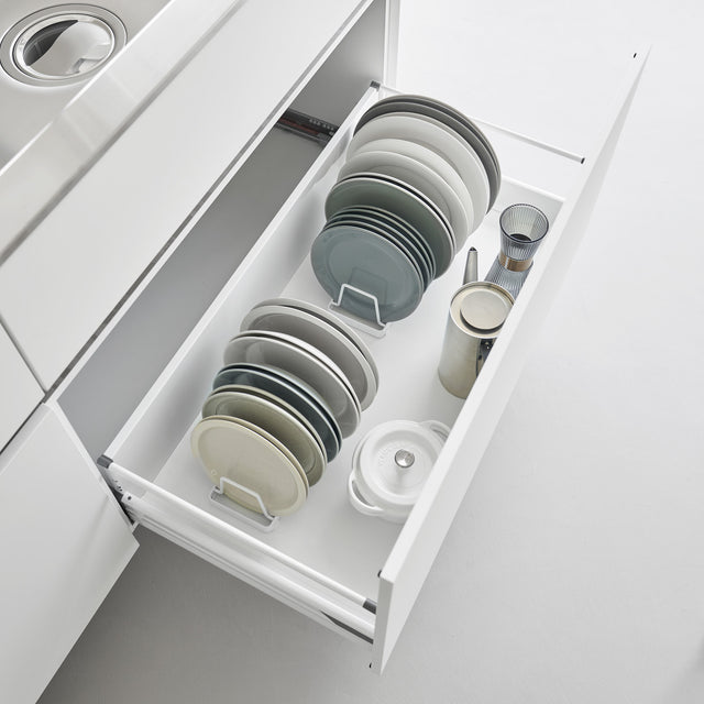 Lite hvitt stativ til tallerkener, brukt i kjøkkenskap for organisering av servise.