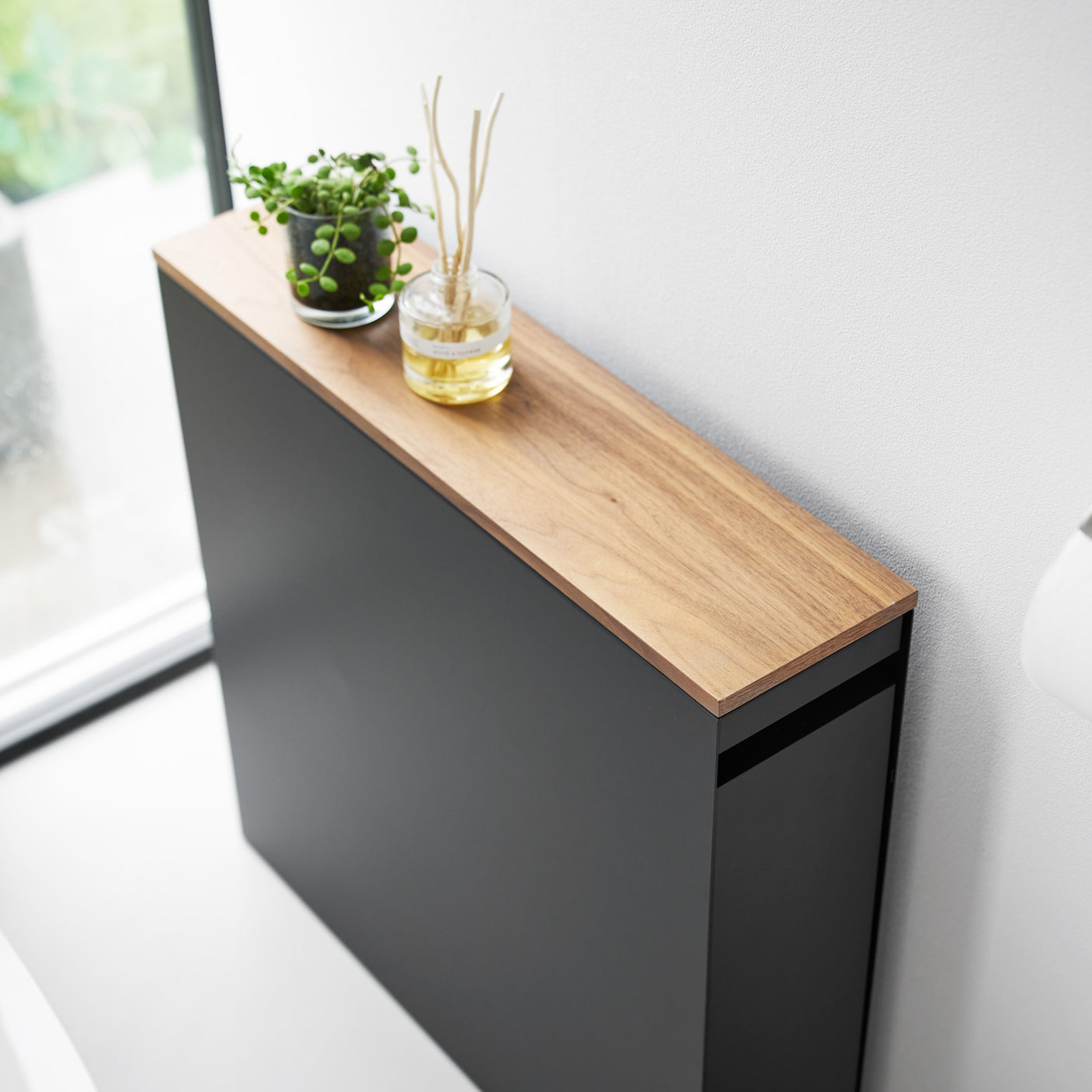 Oppbevaringshylle med hjul og skyvbar treplate for toalettpapir og rengjøringsartikler.