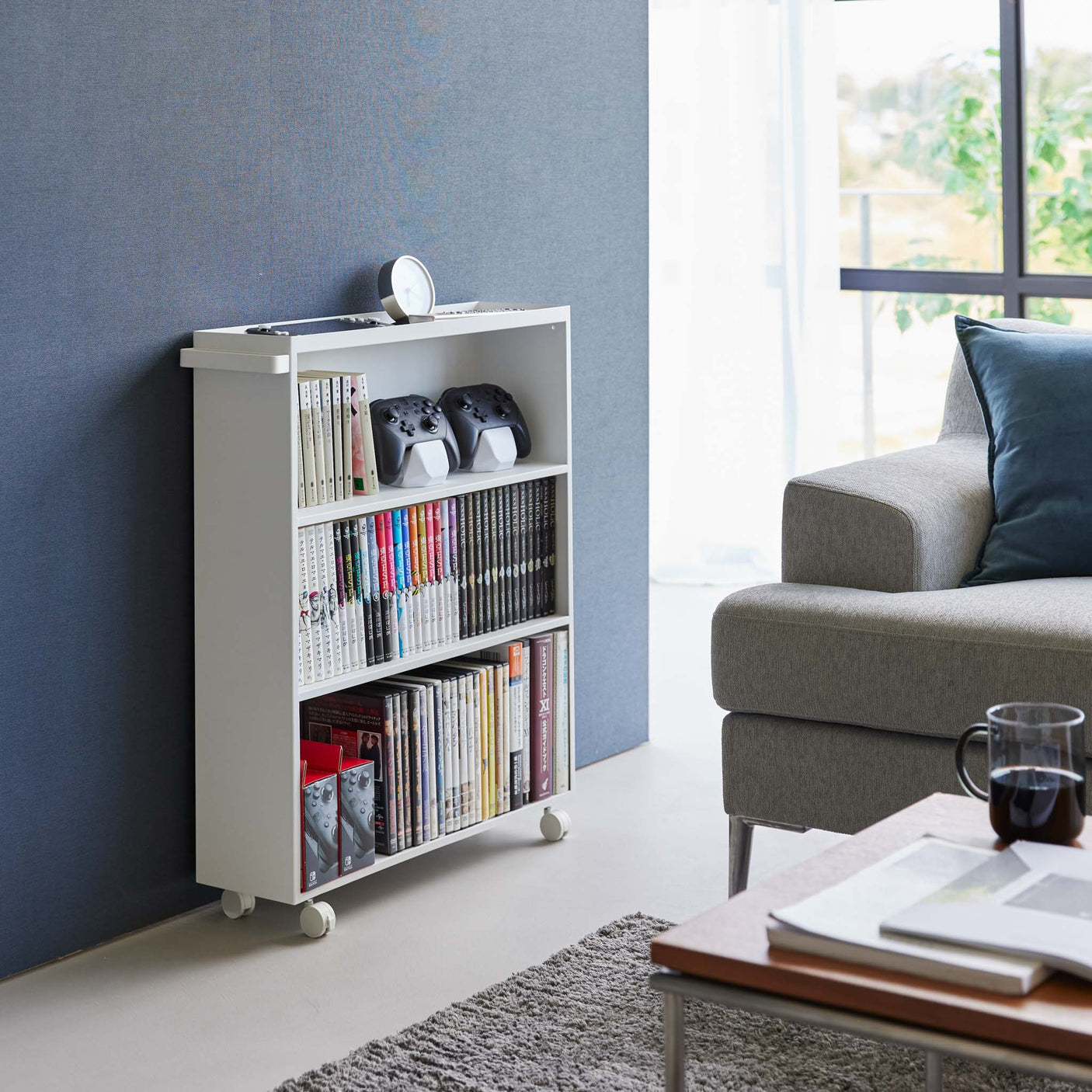 Hvit bokvogn ved siden av kontorpult i rom med blå vegg.