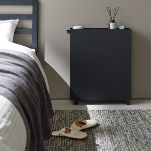 Sort oppbevaringsvogn med tre hyller plassert ved siden av skrivebord.