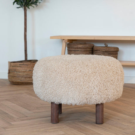 Inverness puff i lys brun fuskepels med mørke treben på hvit bakgrunn