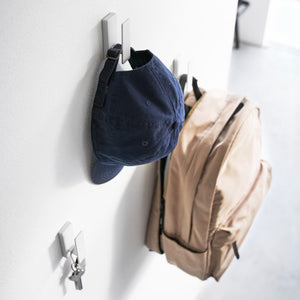 3-pakning veggkroker i hvit metall plassert i gang for klær og tilbehør.