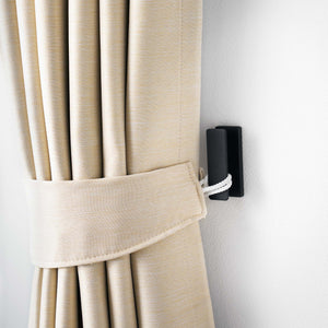 Veggmonterte sorte metallkroker brukt i entré for nøkler og vesker.