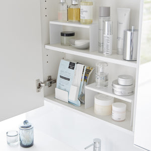 Flere stabelbare kjøkkenhyller organisert på benk med krydder.