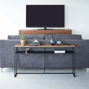 Konsollbord i sort metall med hylle under TV i stue.