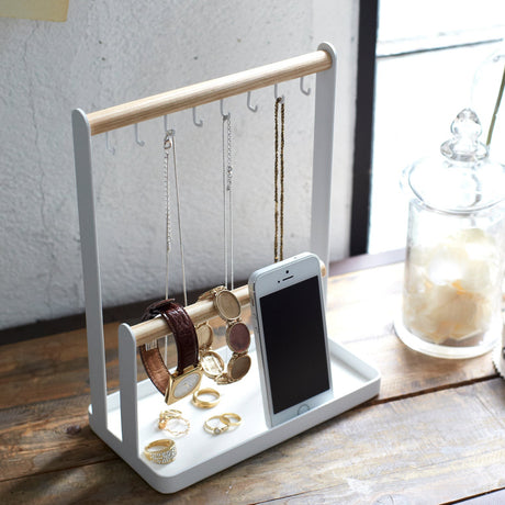 Smykkestativ med metallramme og trestenger, plassert på et bord med smykker.