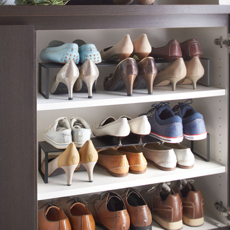 Sort skohylle i stål, justerbar i bredden og stabelbar for praktisk oppbevaring.