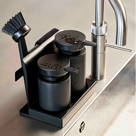 Oppvasksett i sort metall og steintøy plassert ved moderne kjøkkenkran på benkeplate