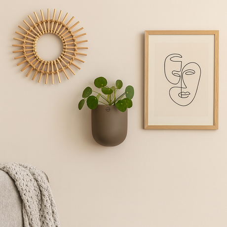 Vegghengt keramikkpotte med plante, stylet med ramme og dekorativ rund veggdekor.