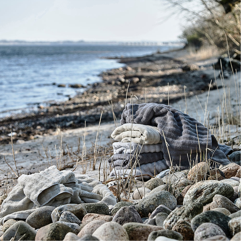 Mykt håndkle i dempet grå farge brettet på bad