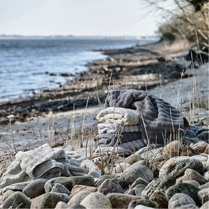 Mykt håndkle i dempet grå farge brettet på bad
