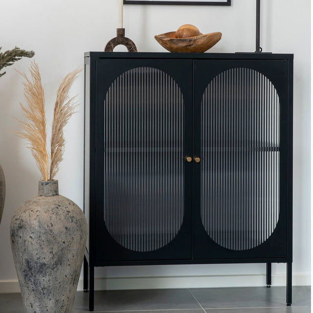 Svart oppbevaringsskap med riflede glassdører og messinghåndtak.