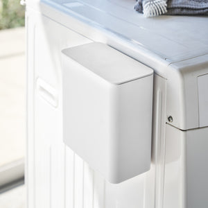 Hvit magnetisk oppbevaringsboks festet på vaskemaskin.