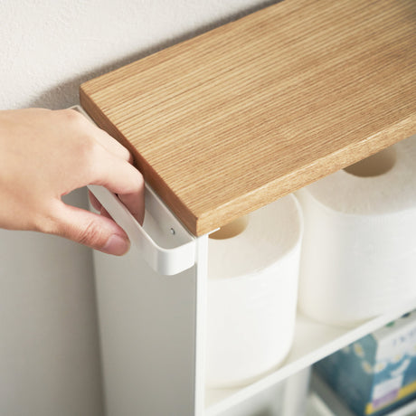 Hylle med plass til toalettpapir, rengjøringsmidler og bøker.