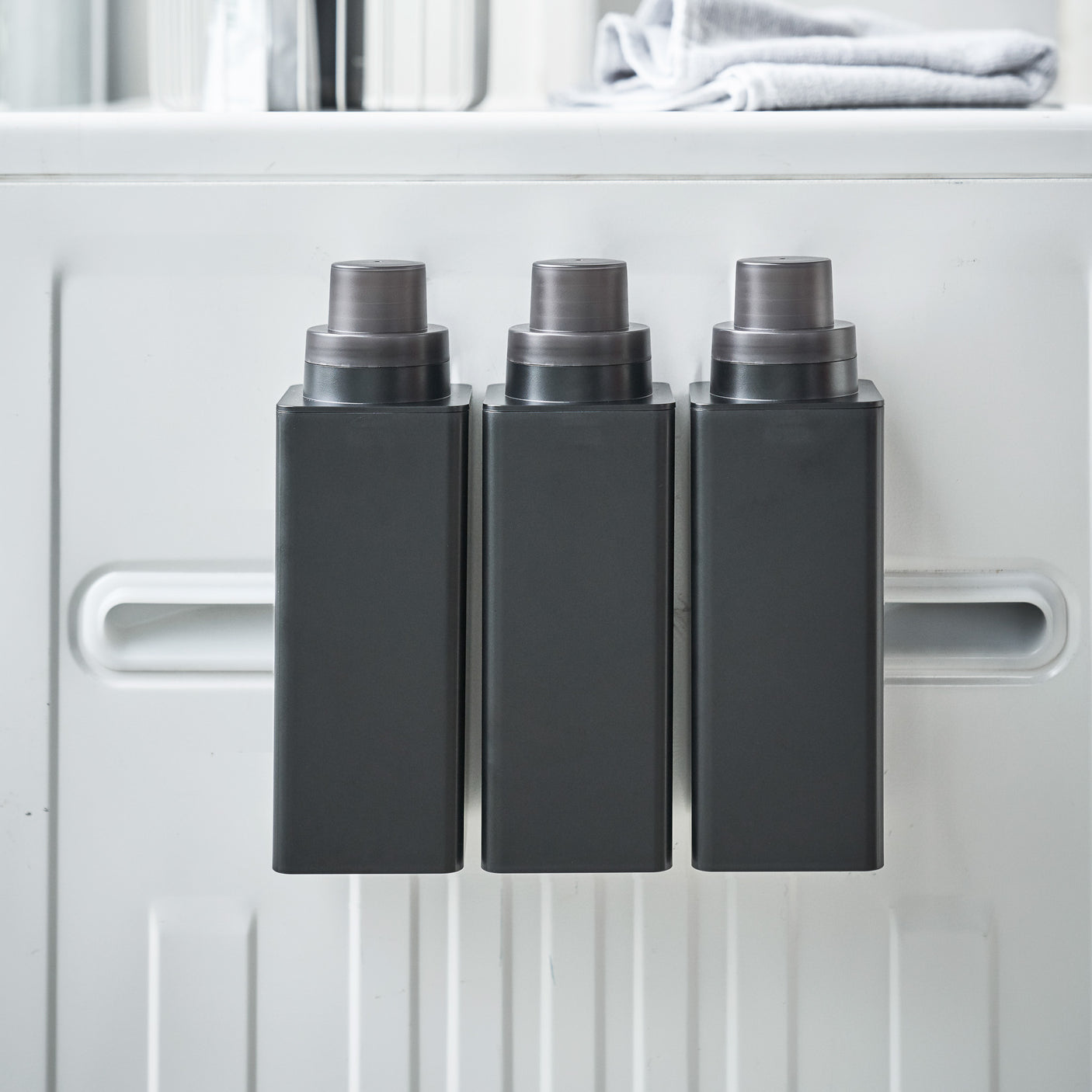 Person fyller opp sort magnetisk flaske med oppvaskmiddel.