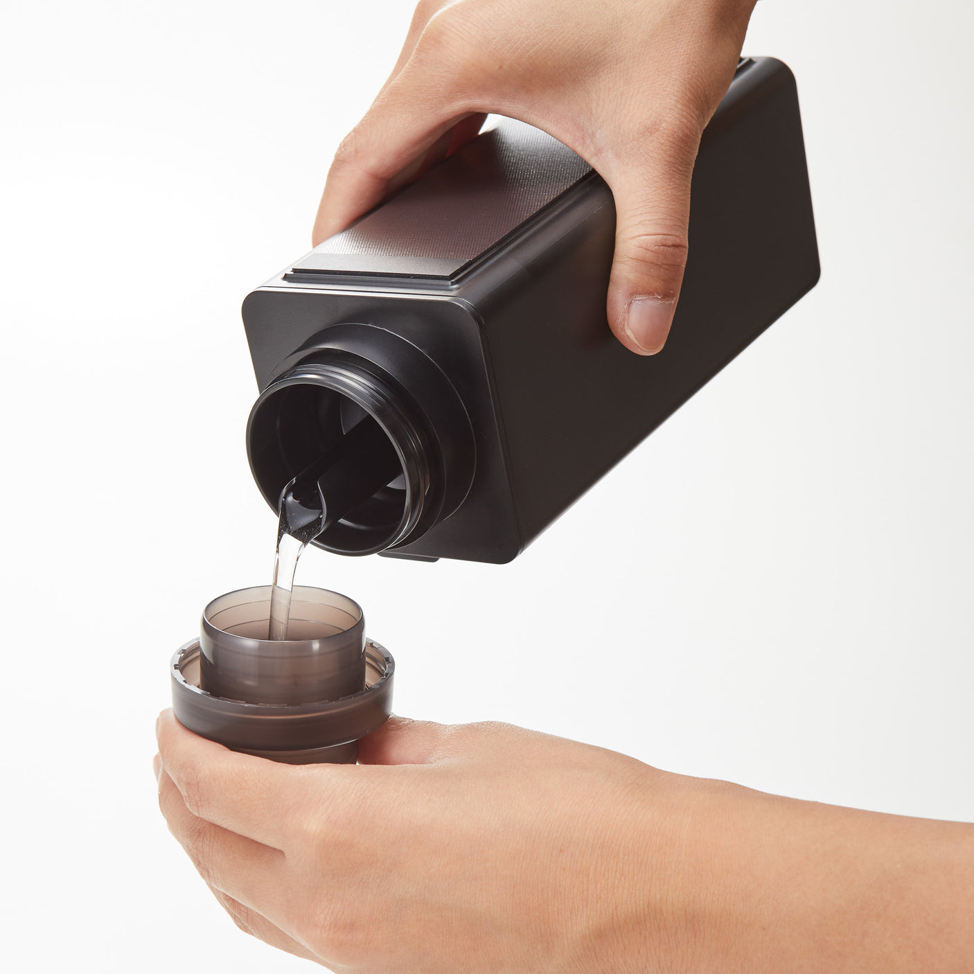 Flaske i sort plast med magnet bakside festet på vaskemaskin.