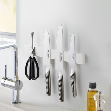 Knivholder i hvitt med kniver og kjøkkenutstyr.