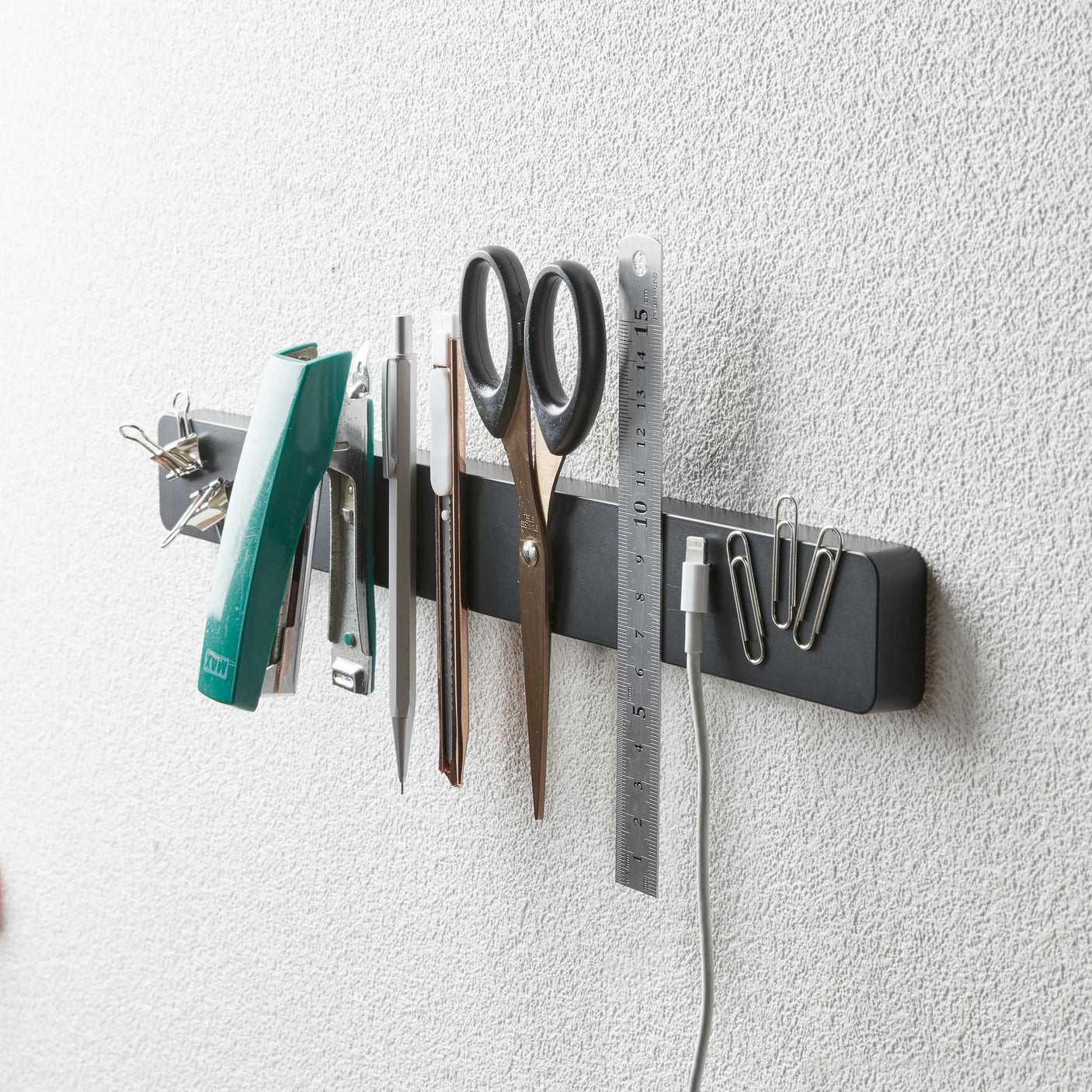 Sort magnetisk knivholder med kniver og kjøkkenutstyr.