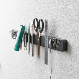 Sort magnetisk knivholder med kniver og kjøkkenutstyr.