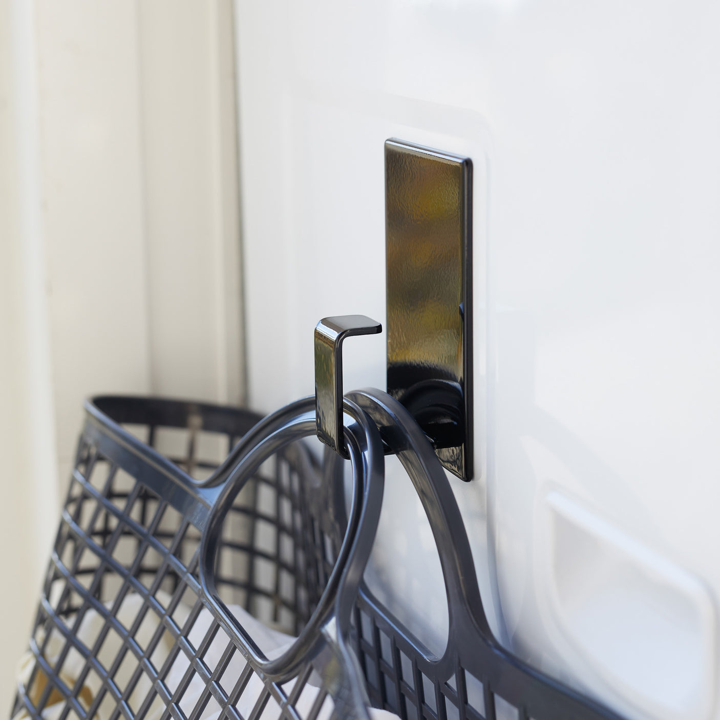 Magnetisk krok holder skittentøyskurv på vaskemaskin.