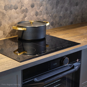 Nærbilde av Hexagon mørk betong fliser fra Lindas Dekor som gir en eksklusiv betonglook bak kokeplaten på kjøkkenet.