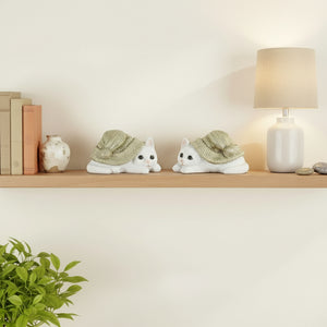 To små kattefigurer i polyresin med grønne luer på hvit bakgrunn