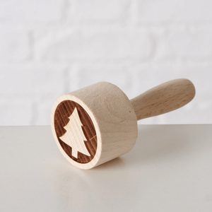Kakestempel i tre med juletre­motiv, liggende på lys overflate.