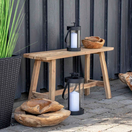 Sort lanterne på terrasse ved trebenk