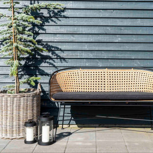 Sorte lanterner ved rottingsofa utendørs