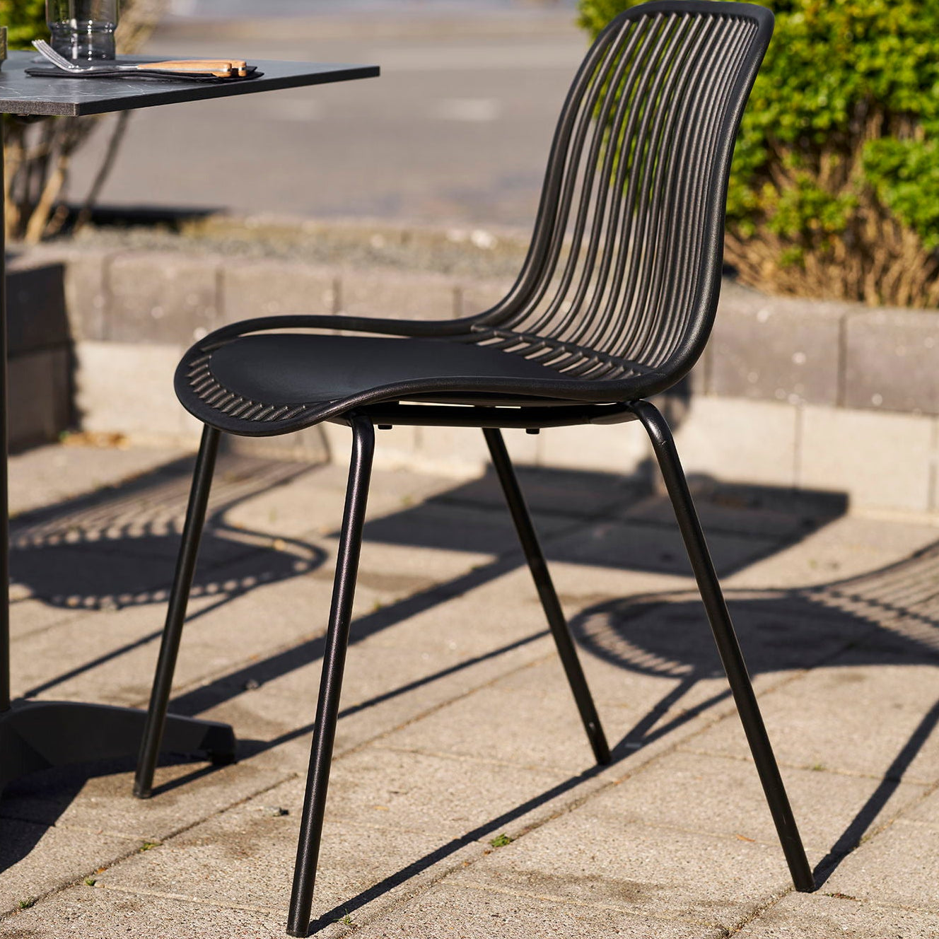 Lett sort utestol brukt ved bord på terrasse