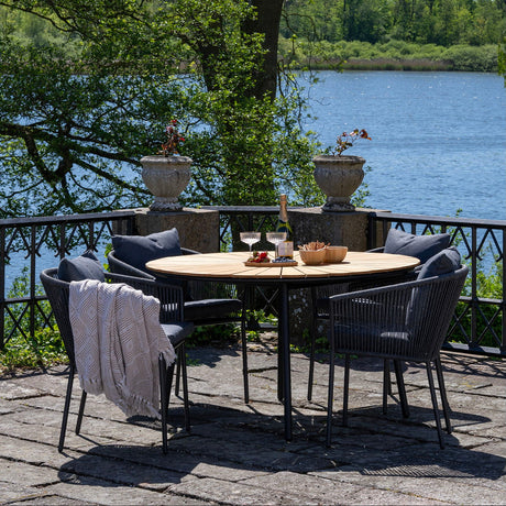 Spisestol utendørs med mørk grå pute og lett ramme