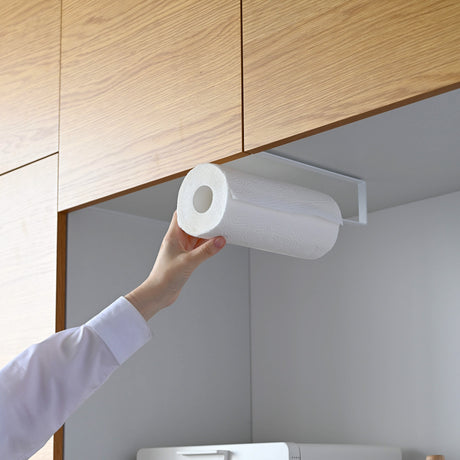 Person monterer kjøkkenpapir på stativ under skap