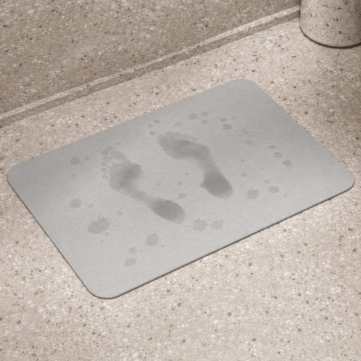 Grå baderomsmatte i diatomitt med våte fotavtrykk på overflaten