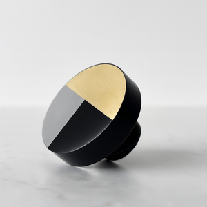 Dekorativ knott i svart, hvit og gull på rustikk trebakgrunn – perfekt til skuffer og skap.