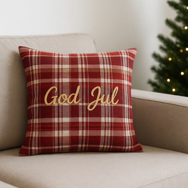 "Putetrekk i rødt rutemønster med teksten God Jul, plassert i beige sofa med juletre i bakgrunnen – klassisk julepynt til stue.