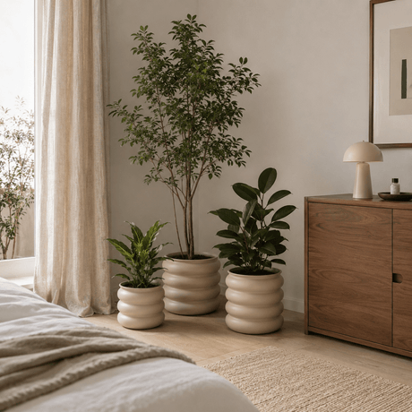 Tre lysebrune blomsterpotter med grønne planter plassert på gulvet i et lyst og moderne soverom. - Lindas dekor 