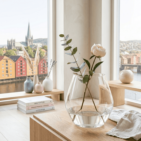 Arja glassvase klar rund 23 x 23 cm stylet med blomster på bord ved stort vindu i lyst nordisk hjem.