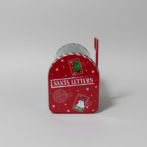 Grønn og rød julepostkasse brukt som dekor på bord med julelys i bakgrunnen