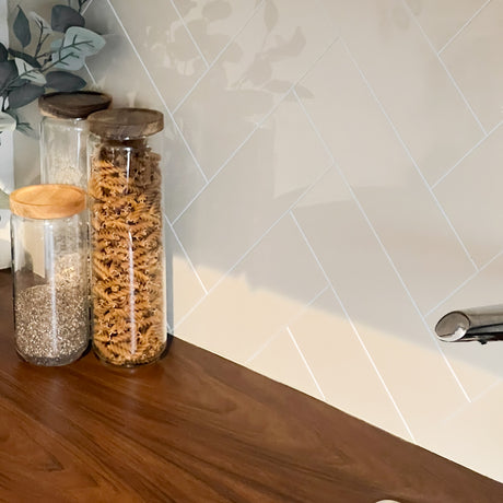 Hailey beige fliser med høyglanset finish montert i fiskebensmønster over kjøkkenbenk i tre.