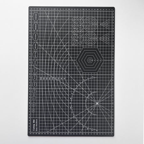 Svart skjærematte med hvite linjer og mønster for presise kutt, ideell for hobby og håndverk.