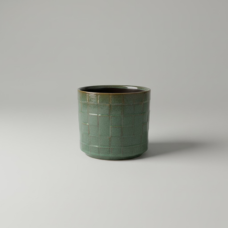 Firkantet grønn blomsterpotte i keramikk på hylle med planter, skandinavisk interiør