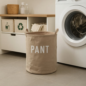 Beige oppbevaringskurv i tekstil med “PANT”-trykk