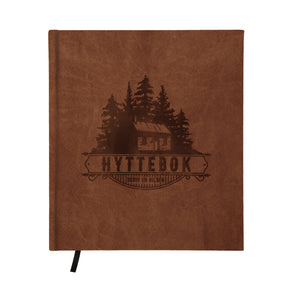 Hyttebok i brun farge med preget motiv av hytte og trær, 21×24 cm