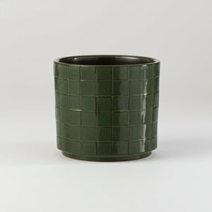 Firkantet grønn blomsterpotte i keramikk på hylle med planter, skandinavisk interiør