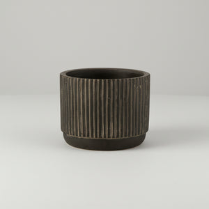 Detaljbilde av liten keramikkpotte med stripet design i svart og brune toner
