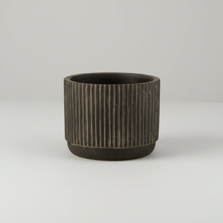 Detaljbilde av liten keramikkpotte med stripet design i svart og brune toner